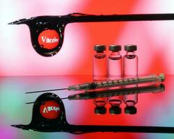 Small vaccine injection bottle transparent reflection refraction red led light background hypodermic syringe needle droplet type covid 19 vaccine photo