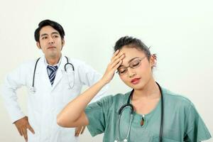 joven asiático malayo chino masculino hembra médico en blanco antecedentes dolor de cabeza enojado irritado mano en cabeza foto