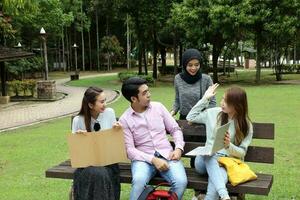 joven asiático malayo chino hombre mujer al aire libre parque libro archivo carpeta ordenador portátil computadora teléfono sentar estar estudiar mezclarse foto