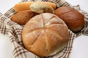 recién horneado un pan pan bollo rodar redondo largo mezcla verdad envuelto en a cuadros cocina tela servilleta toalla terminado blanco antecedentes foto