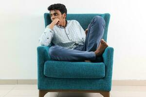 A young south east Asian sit pose look think work study emotion feelings on a blue single sofa. He is adhd and autistic photo