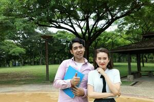 young asian malay chinese man woman outdoor park walk stand study talk discuss laptop file book backpack pose happy mingle photo