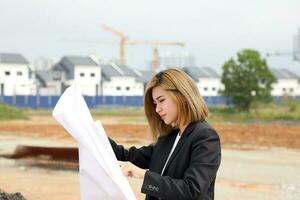 woman chinese malay worker engineer management at construction site reading seeing plan photo