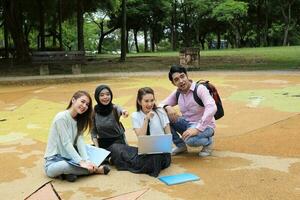 joven asiático malayo chino hombre mujer al aire libre parque libro archivo carpeta ordenador portátil computadora teléfono sentar estar estudiar mezclarse foto