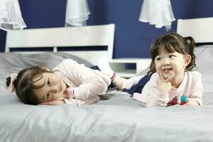 Two girl children lying on bed looking forward posing photo