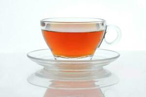 Clear licker tea in a transparent glass cup saucer spoon on white background photo