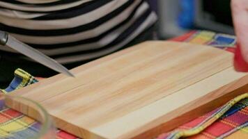mayor mujer cortar rojo manzana con un cuchillo en un corte tablero en un cocina mesa video