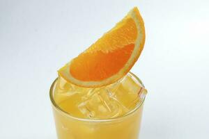 Fresh yellow orange juice in glass with orange slice and ice cube on white background photo