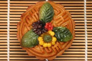 Colorful flower decorated mooncake Chinese mid autumn festival on bamboo food mat background photo