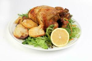 Whole roasted grilled chicken poultry bird with baked potato vegetable salad tomato lemon on white background photo