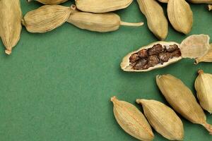 Cardamom fragrant spice seed closeup macro on green paper background photo