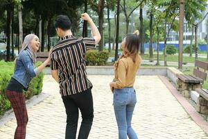 Young Asian Malay man woman outdoor green park walk talk discuss mingle sign show photo