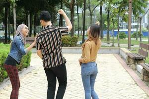 joven asiático malayo hombre mujer al aire libre verde parque caminar hablar discutir mezclarse firmar espectáculo foto