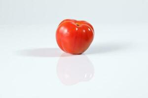 Fresh ripe small shiny red tomato on white background photo