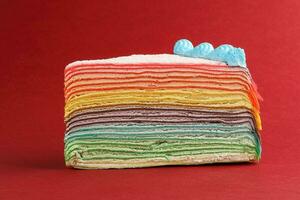 Rainbow crepe layer cake on red background photo