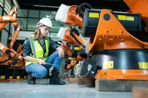 hembra técnico inspeccionando y reparando robótica brazo en robots hangar y prueba el operación de el máquina después siendo usado para un mientras, como bien como actualización el software y calibración foto