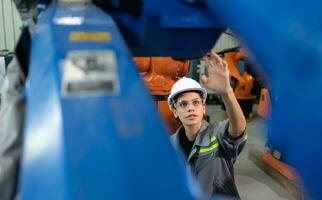 A female engineer installs a program on a robotics arm in a robot warehouse. And test the operation before sending the machine to the customer. photo