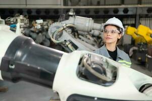 A female engineer installs a program on a robotics arm in a robot warehouse. And test the operation before sending the machine to the customer. photo