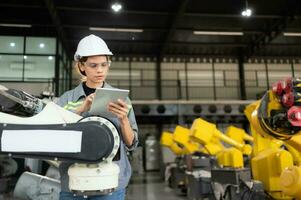 A female engineer installs a program on a robotics arm in a robot warehouse. And test the operation before sending the machine to the customer. photo