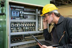 Senior engineer inspects the electrical system and repairs the mechanical system in the machine control cabinet. in order for the machine to return to normal operation photo