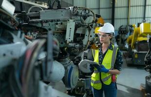 A female engineer installs a program on a robotics arm in a robot warehouse. And test the operation before sending the machine to the customer. photo