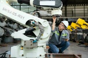 A female engineer installs a program on a robotics arm in a robot warehouse. And test the operation before sending the machine to the customer. photo