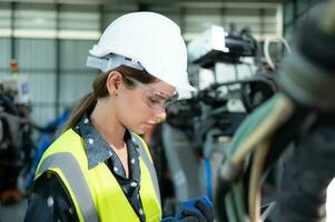 A female engineer installs a program on a robotics arm in a robot warehouse. And test the operation before sending the machine to the customer. photo