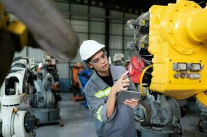 A female engineer installs a program on a robotics arm in a robot warehouse. And test the operation before sending the machine to the customer. photo