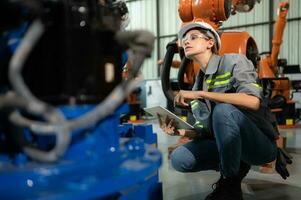 A female engineer installs a program on a robotics arm in a robot warehouse. And test the operation before sending the machine to the customer. photo
