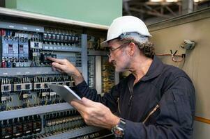 mayor ingeniero inspecciona el eléctrico sistema y refacción el mecánico sistema en el máquina controlar gabinete. en orden para el máquina a regreso a normal operación foto