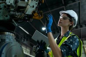 A female engineer installs a program on a robotics arm in a robot warehouse. And test the operation before sending the machine to the customer. photo