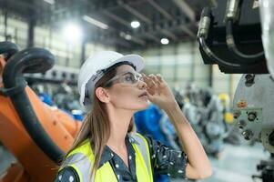 A female engineer installs a program on a robotics arm in a robot warehouse. And test the operation before sending the machine to the customer. photo