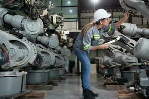 A female engineer checking documented items after installing a program on a robotic arm in a robotic warehouse and test the operation photo