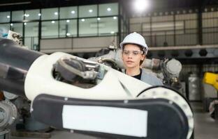 A female engineer installs a program on a robotics arm in a robot warehouse. And test the operation before sending the machine to the customer. photo