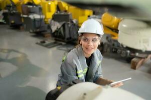 A female engineer installs a program on a robotics arm in a robot warehouse. And test the operation before sending the machine to the customer. photo