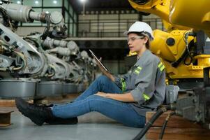 A female engineer installs a program on a robotics arm in a robot warehouse. And test the operation before sending the machine to the customer. photo
