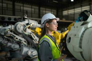 en el robots depósito, hembra ingeniero felizmente con actualización software y calibrando un robótica brazo. foto