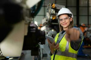 In the robots warehouse, Female engineer happily with updating software and calibrating a robotics arm. photo