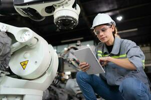 A female engineer installs a program on a robotics arm in a robot warehouse. And test the operation before sending the machine to the customer. photo