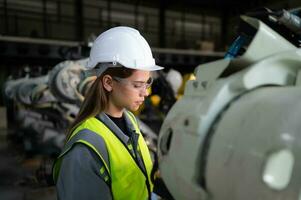 In the robots warehouse, Female engineer happily with updating software and calibrating a robotics arm. photo