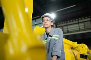 A female engineer installs a program on a robotics arm in a robot warehouse. And test the operation before sending the machine to the customer. photo