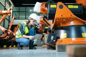 hembra técnico inspeccionando y reparando robótica brazo en robots hangar y prueba el operación de el máquina después siendo usado para un mientras, como bien como actualización el software y calibración foto