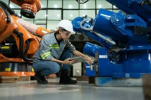 A female engineer installs a program on a robotics arm in a robot warehouse. And test the operation before sending the machine to the customer. photo