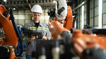 After installing a program on the robotic arm, a female engineer with a robotic arm controller performs a test run. photo