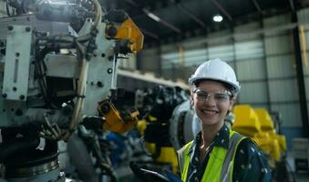 A female engineer installs a program on a robotics arm in a robot warehouse. And test the operation before sending the machine to the customer. photo