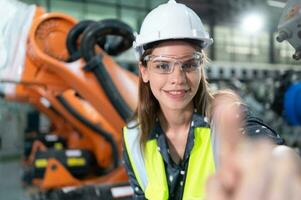 In the robots warehouse, Female engineer happily with updating software and calibrating a robotics arm. photo