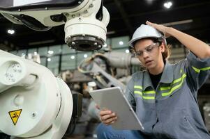 A female engineer installs a program on a robotics arm in a robot warehouse. And test the operation before sending the machine to the customer. photo