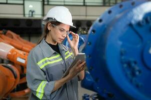 A female engineer installs a program on a robotics arm in a robot warehouse. And test the operation before sending the machine to the customer. photo