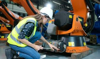 hembra técnico inspeccionando y reparando robótica brazo en robots hangar y prueba el operación de el máquina después siendo usado para un mientras, como bien como actualización el software y calibración foto