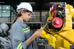 A female engineer installs a program on a robotics arm in a robot warehouse. And test the operation before sending the machine to the customer. photo